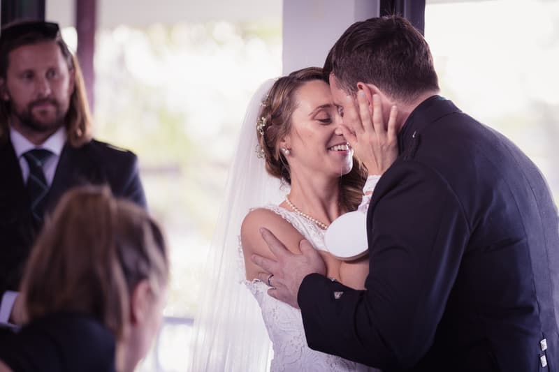 Bride Francesca and groom Ben share an intimate moment at the reception in The Malouf Room, Toowong Rowing Club, with guests visible in the background.
