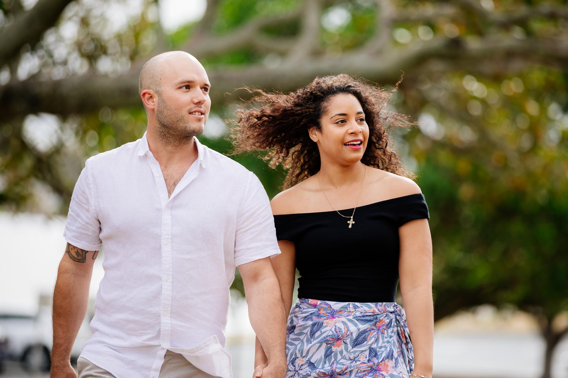 The couple walking hand in hand under a large tree at Shorncliffe beachfront.