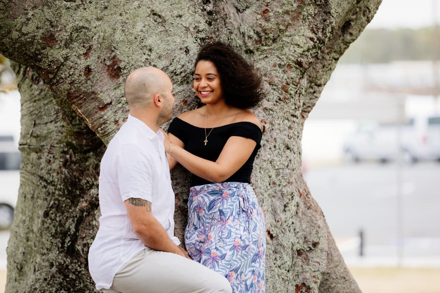 The couple sitting close under a large tree, enjoying each other's company.