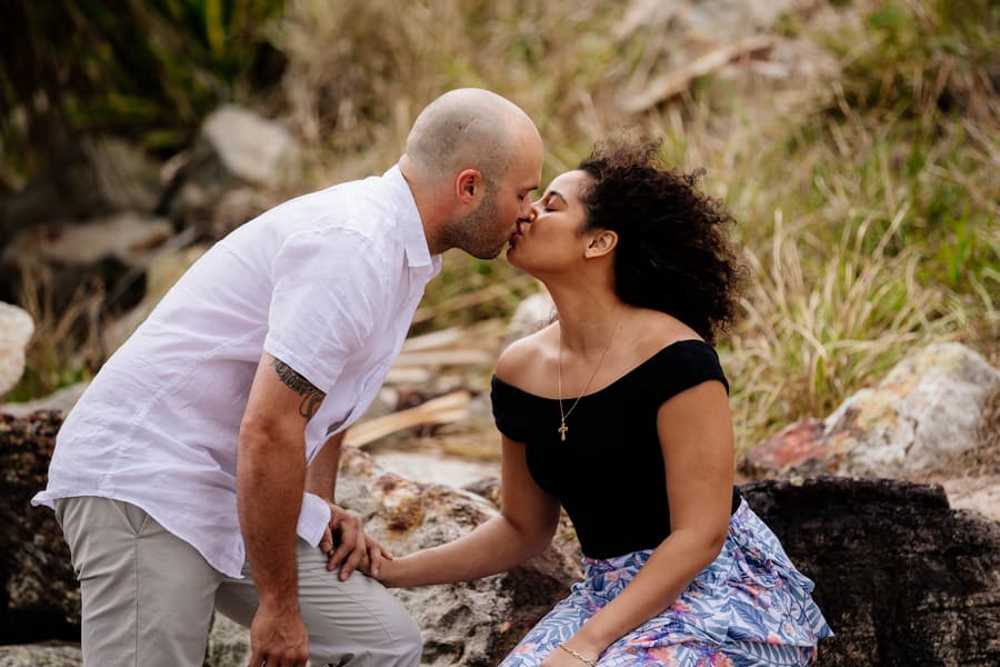 Couple kissing while sitting on rocks at Shorncliffe beachfront.