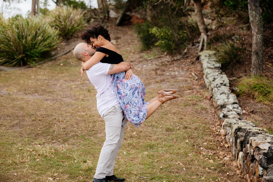 The couple embracing, one lifting the other off the ground, both smiling.
