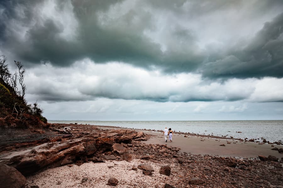 Couple standing on a rocky beach with dramatic clouds overhead at Shorncliffe.