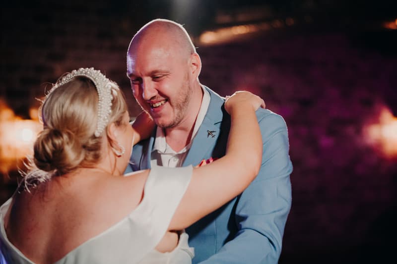 Bride Jacquelyne and groom Arran share a dance at the reception stage inside Sandstone Point Hotel — Cellar.