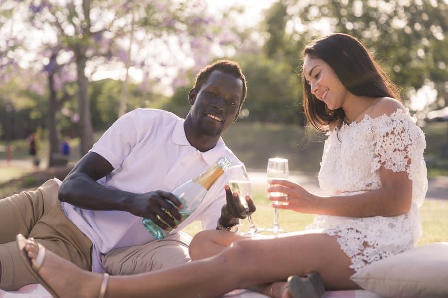 The couple sitting closely, holding champagne glasses, smiling broadly at the camera.