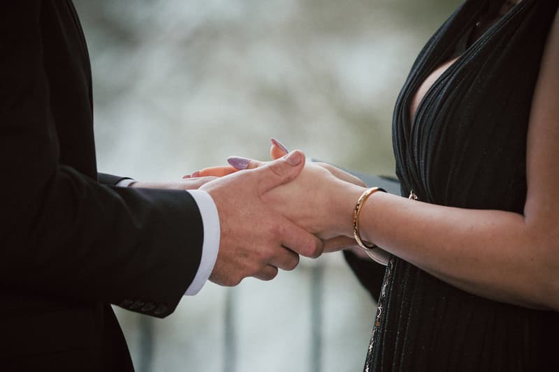 The bride and groom hold hands during their wedding ceremony at Sandstone Point Hotel — The Pavilion.