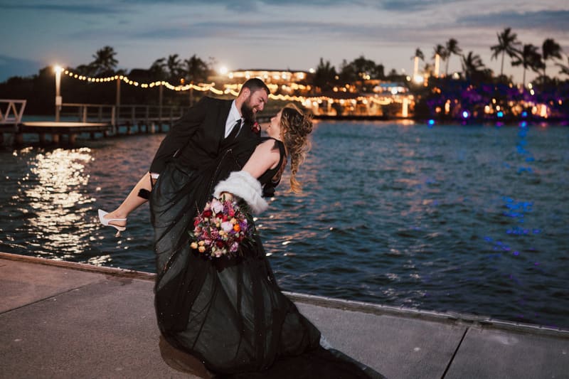 Christopher dips Jayme holding a bouquet near the water. Wedding photographer Brisbane by She Said Yes.