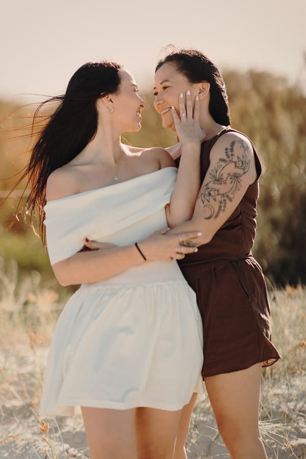 The couple embracing closely on the sandy dunes at Woorim Beach, gazing into each other's eyes with affection.