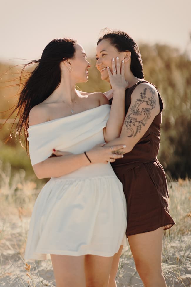 The couple embracing closely on the sandy dunes at Woorim Beach, gazing into each other's eyes with affection.