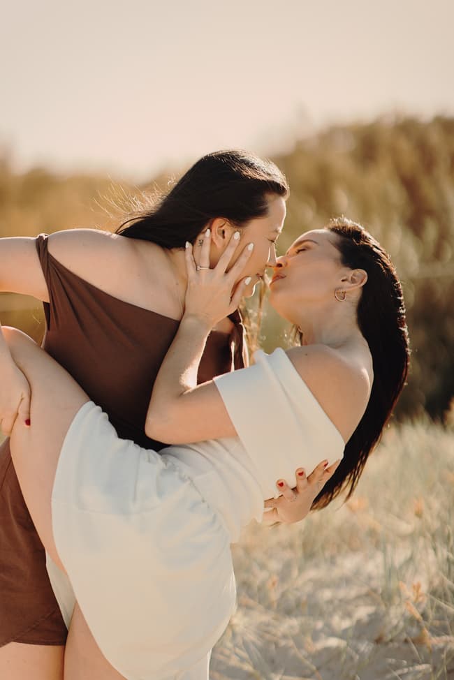 Close-up of the couple kissing on the sandy dunes at Woorim Beach, with sunlight highlighting their expressions.