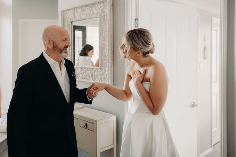 The bride Libby shares a moment with an older man, likely her father, inside a room at The Tides, The Water's Edge.