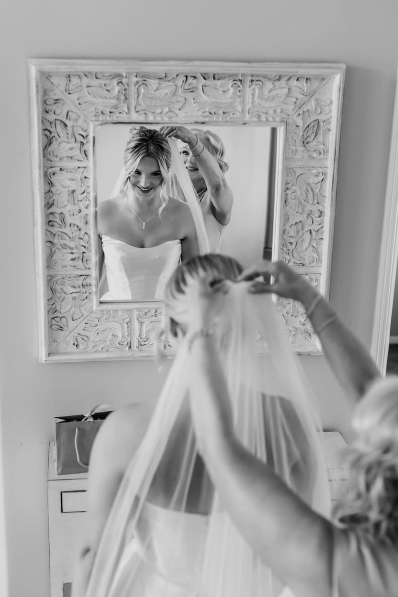 The bride Libby is having her veil adjusted by an older woman, possibly her mother, reflected in a decorative mirror. Elopement photographer Brisbane by She Said Yes.