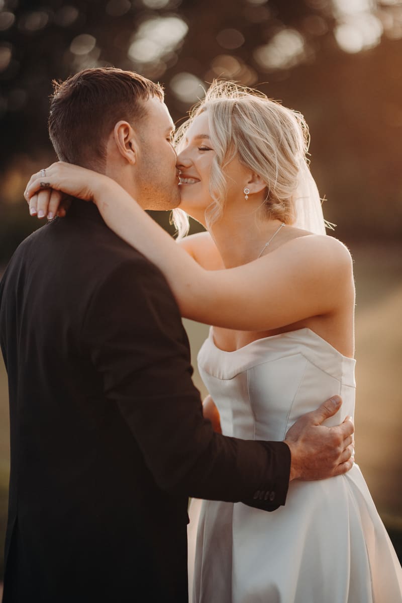Bride Libby and groom Kyle embrace and share a kiss during their couple portraits session. Wedding photography by She Said Yes.