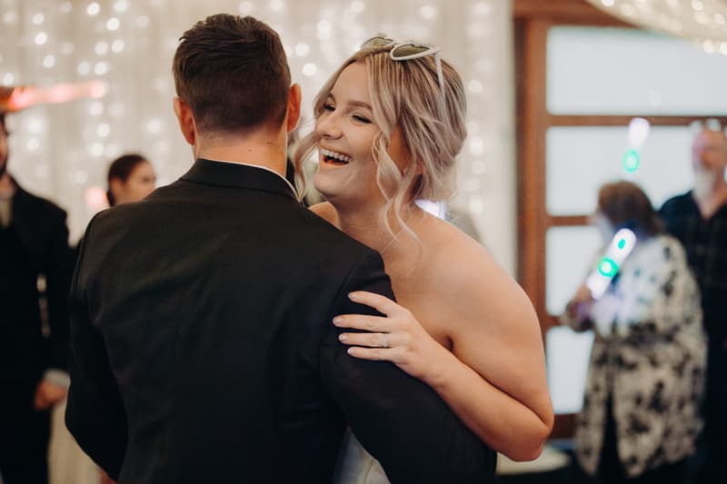 Bride Libby and groom Kyle dance together at the reception in The Pandanus Room at The Tides, with guests visible in the background.