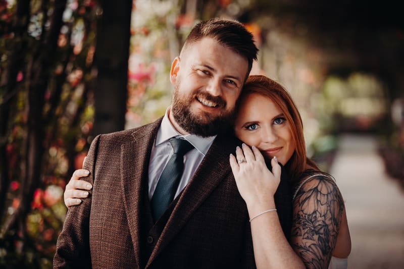 The bride Lilas and groom Kaine pose closely together for couple portraits, with Lilas resting her hand on Kaine's shoulder showing her wedding ring. Brisbane wedding videography by She Said Yes.