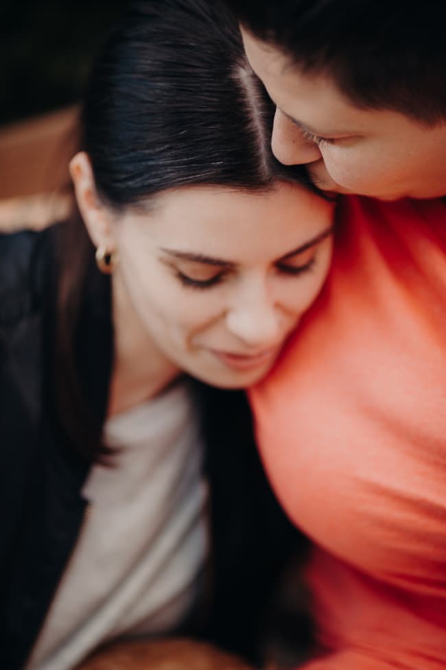 One person resting their head on the other's shoulder, eyes closed, in a tender moment.