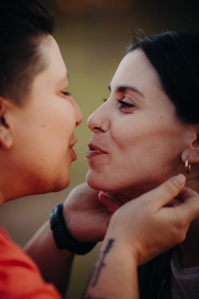 The couple leaning in for a kiss, hands gently holding each other's faces.