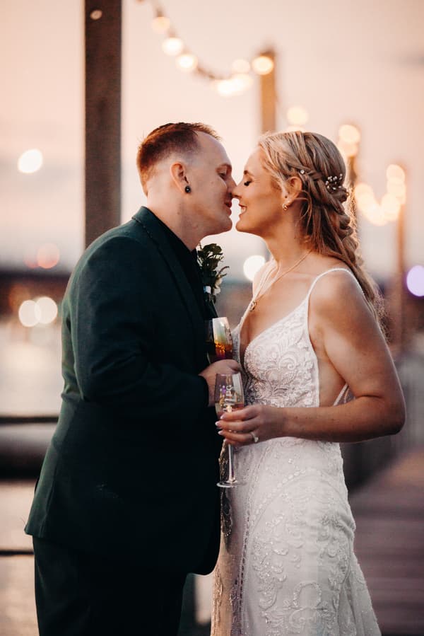 Madison and Brendon share a close moment holding champagne glasses at Sandstone Point Hotel during their couple portraits session.