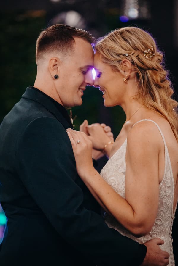 Bride Madison and groom Brendon share a close moment dancing at the reception in the Pumicestone Room at Sandstone Point Hotel.