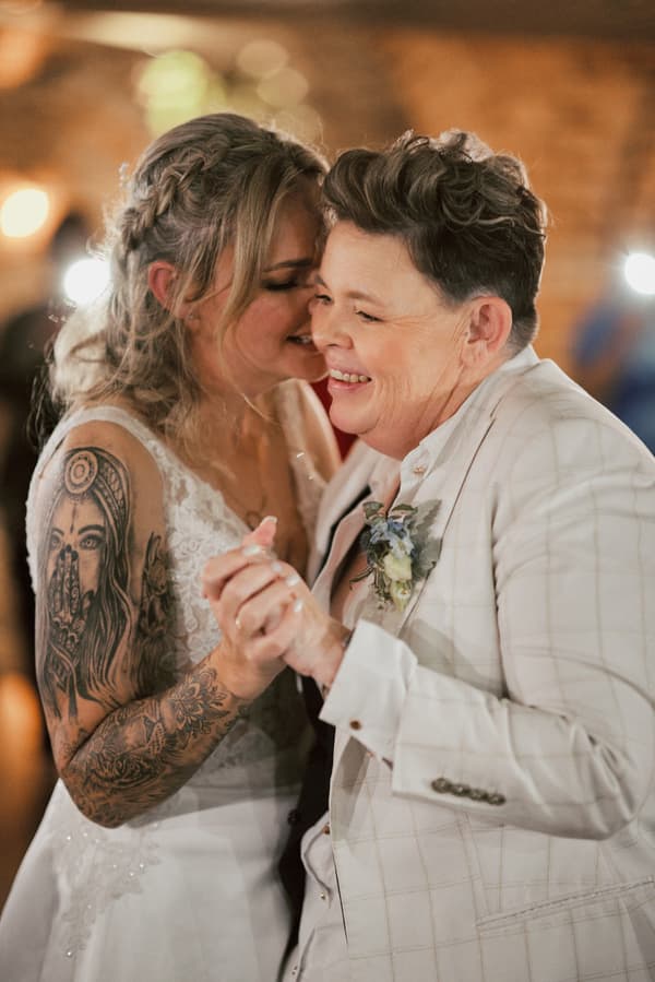 Brides Mandy and Selina share a close moment dancing together at the reception in Sandstone Point Hotel — The Cellar.
