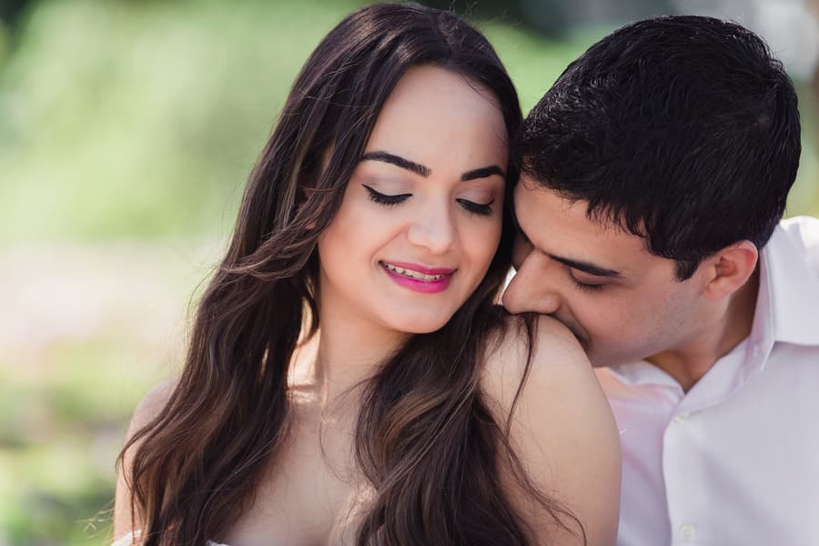 The couple shares an intimate moment, with one leaning in to kiss the other's shoulder at UQ Lakes.