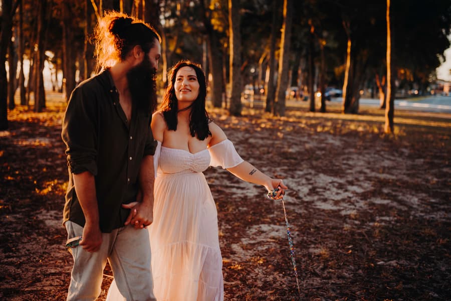 The couple walks hand in hand at Woorim Beach, with the woman smiling warmly at her partner.