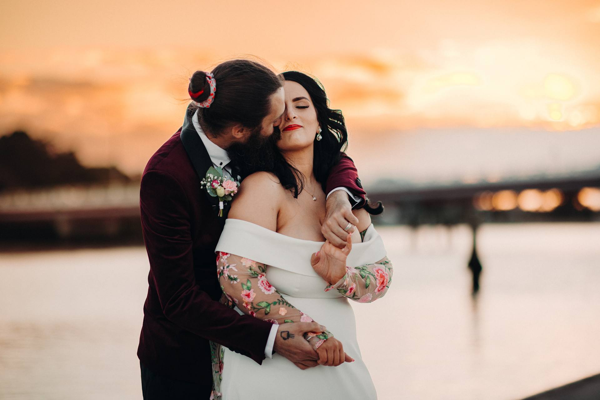 The bride Mindy and groom David embrace during a couple portrait session at Sandstone Point Hotel at sunset, with David kissing Mindy on the cheek as she closes her eyes.
