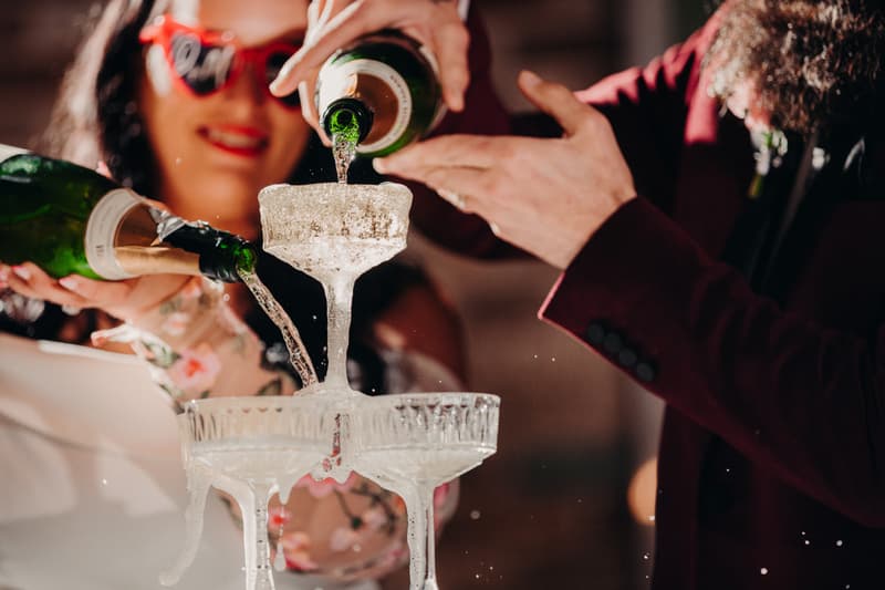 The bride and groom pour champagne into a stacked champagne tower at the Sandstone Point Hotel — Cellar during the reception stage.
