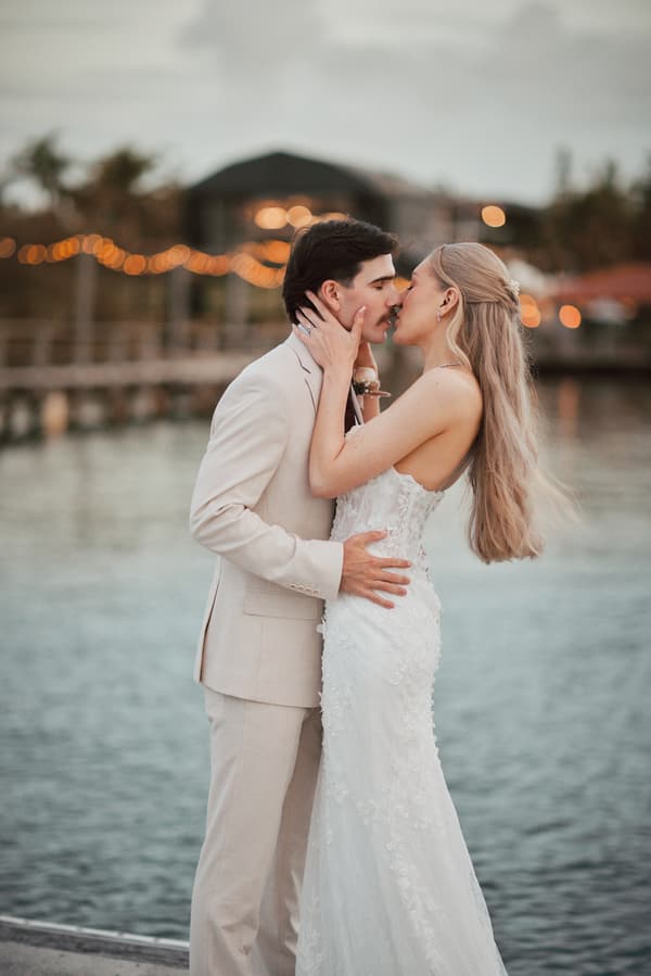 Bride Morgan and groom Joel embrace and lean in for a kiss near the water at Sandstone Point Hotel during their couple portraits session.