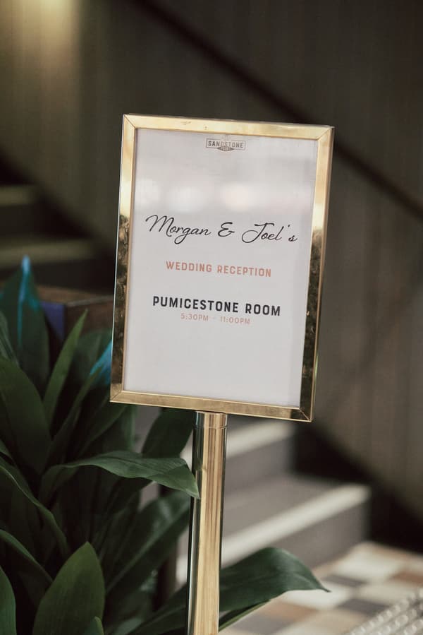 Signage at Sandstone Point Hotel indicating Morgan and Joel's wedding reception in the Pumicestone Room from 5:30 PM to 11:00 PM.