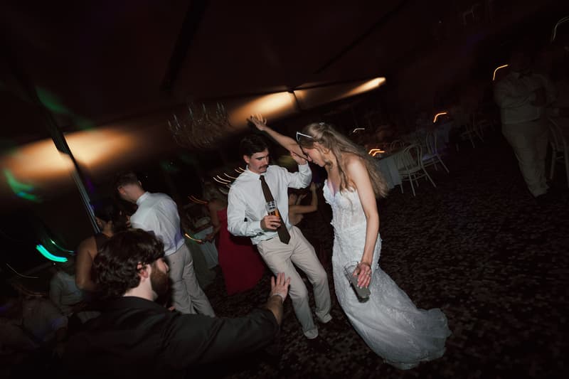 The bride and groom dance together at the reception in The Pumicestone Room at Sandstone Point Hotel, surrounded by guests.