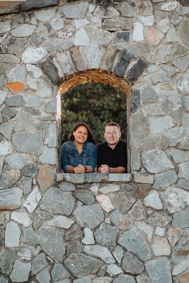 The couple leans out of a stone window at Redcliffe, smiling together.