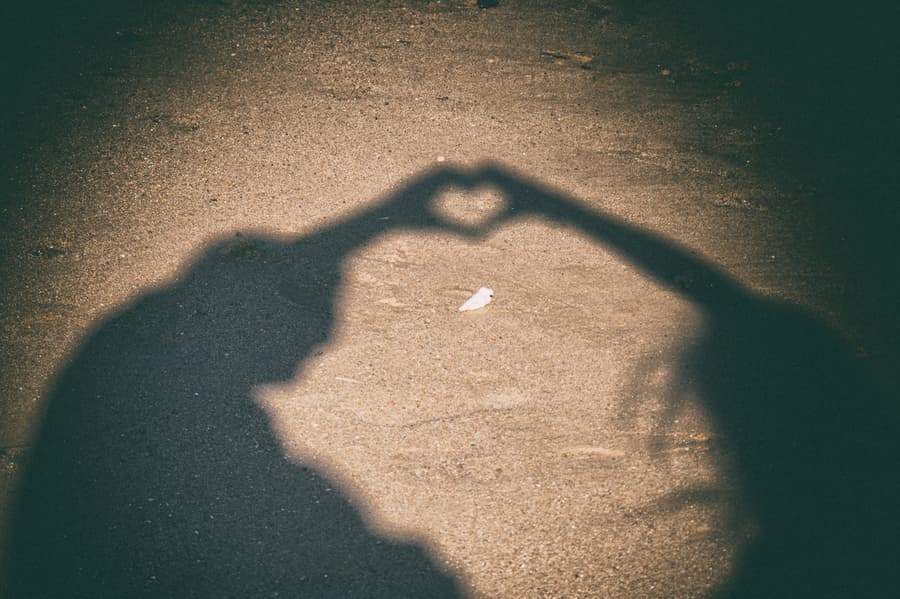 Shadows of a couple on the sand forming a heart shape with their hands at Scarborough Beach.