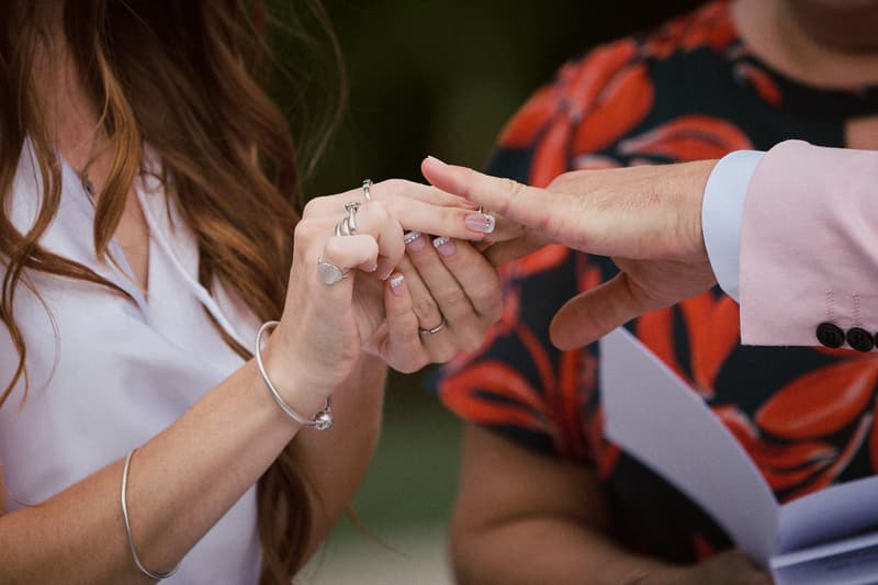 The bride places a ring on the groom's finger during the ceremony at Eatons Hill Hotel — Lakeside.