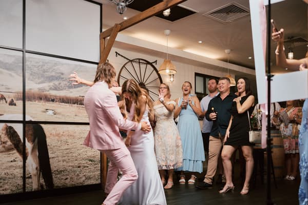 The bride Olivia and groom Jake dance together on the reception stage at White Horse Ranch while guests watch and cheer.