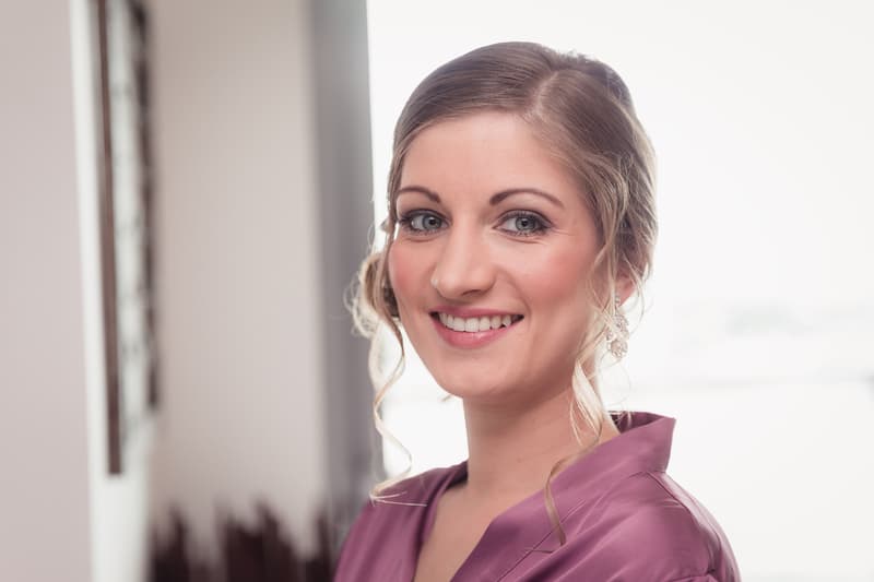 Solo portrait of the bride Maryam wearing a purple robe indoors with a softly lit background.