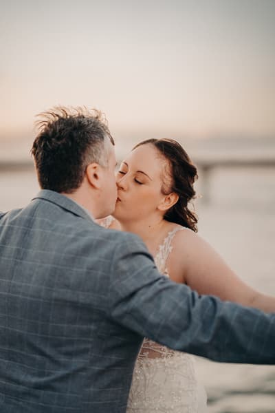 Bride Rebecca and groom Dale share a kiss during their couple portraits session, with a blurred outdoor background. Engagement reception by She Said Yes.