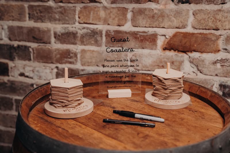 Guest coasters and markers arranged on a wooden barrel table at Sandstone Point Hotel, with a brick wall background.