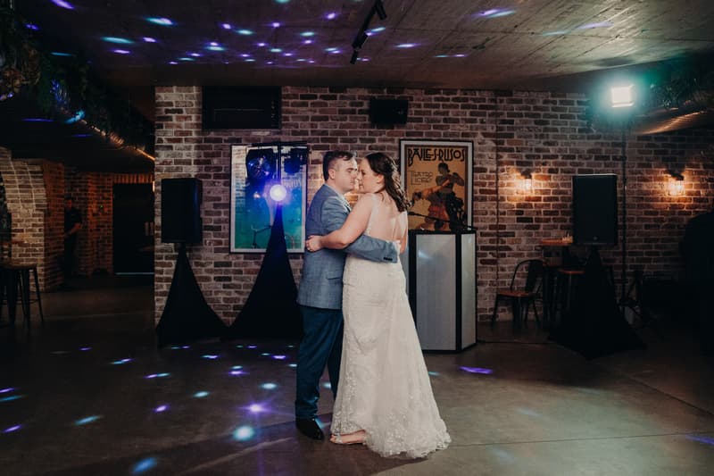 Rebecca and Dale share a dance in the Sandstone Point Hotel — Cellar with exposed brick walls and ambient lighting.