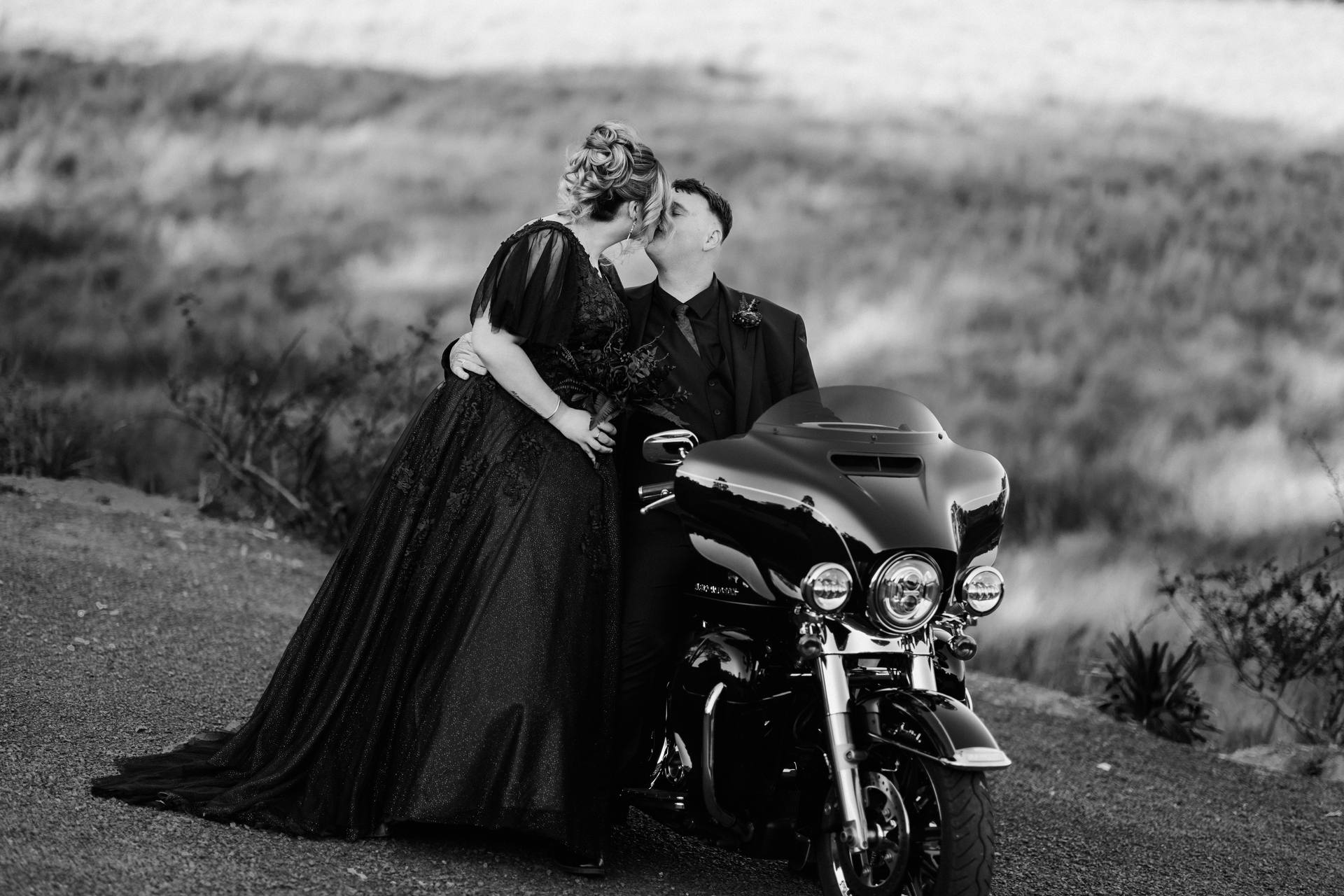 Renae and Adam share a kiss beside a motorcycle at Ocean View Estates during their couple portraits session.