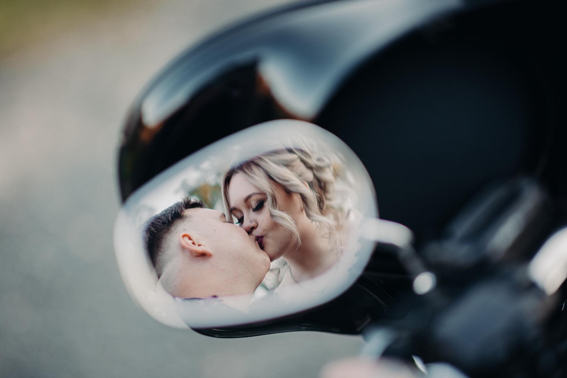 Renae and Adam share a kiss reflected in a motorcycle side mirror at Ocean View Estates during their couple portraits session.