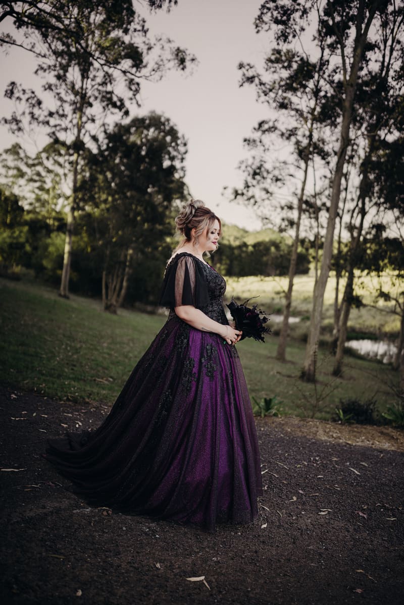 The bride Renae stands alone outdoors, with trees and grass in the background. Elopement photography Brisbane by She Said Yes.