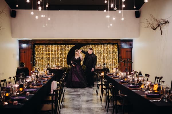Bride Renae and groom Adam dance in the center of the Ocean View Estates Function Room reception stage, with tables set on either side and a backdrop of string lights behind them.