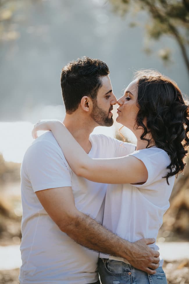 The couple shares a close embrace and kiss, surrounded by soft natural light at Kangaroo Point.