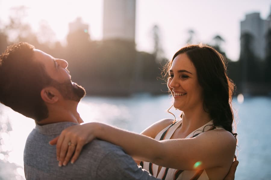 The couple laughing together by the water at Kangaroo Point, with sunlight creating a warm glow.