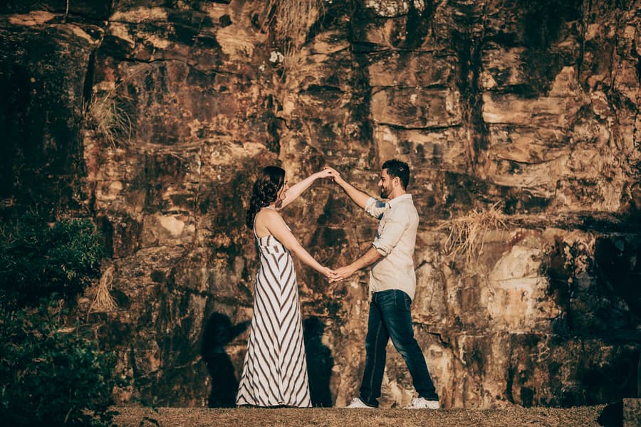 The couple dancing together in front of a rocky cliff at Kangaroo Point, with shadows cast on the rocks.