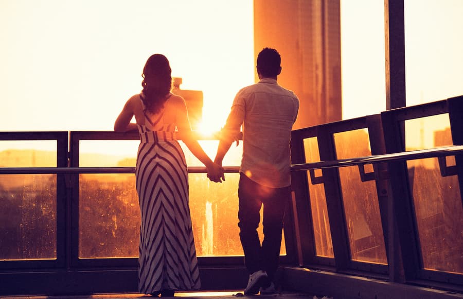 The couple holding hands and watching the sunset at Kangaroo Point, silhouetted against the golden sky.