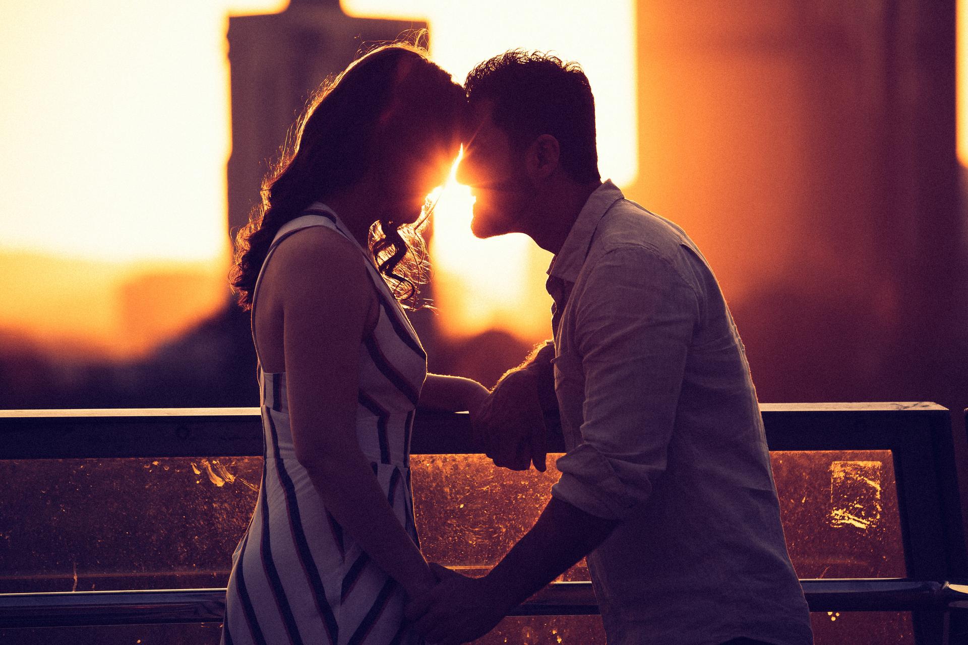 The couple leaning in for a kiss at sunset, with warm light creating a romantic atmosphere at Kangaroo Point.