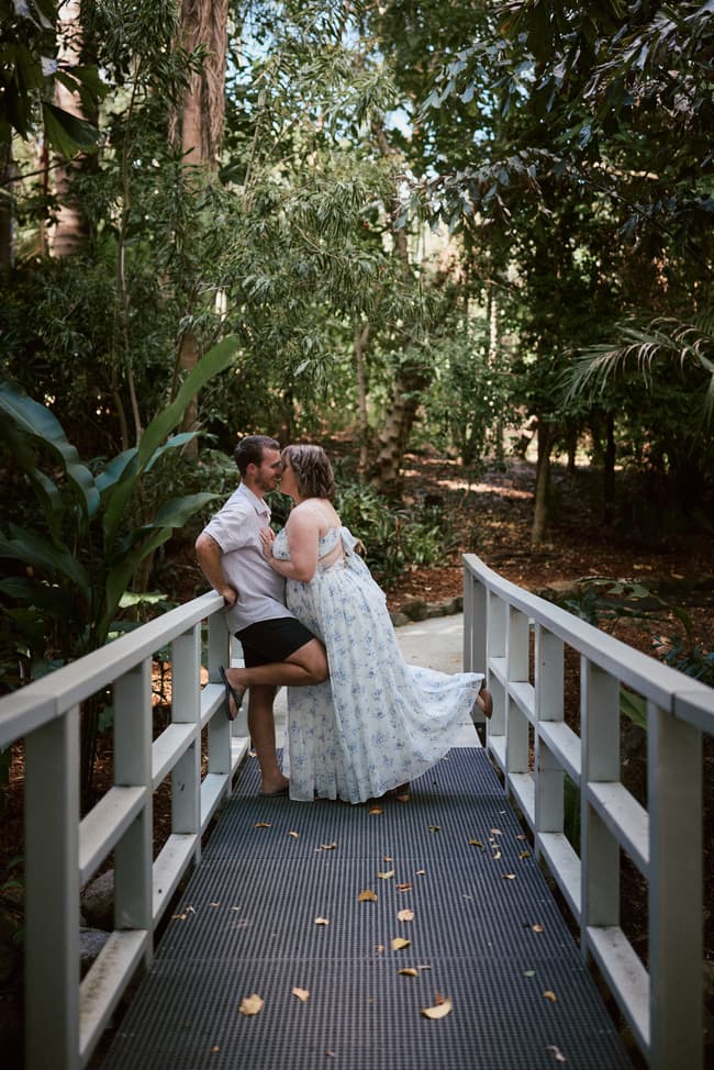 The couple shares a kiss on a bridge surrounded by lush greenery at Brisbane Botanic Gardens.