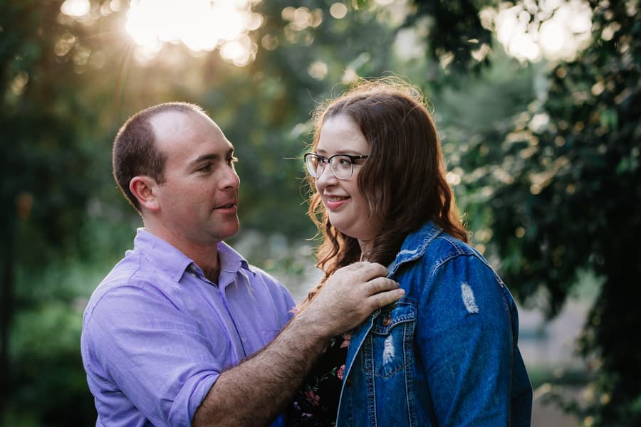 The couple stands close, with the sun setting behind them, creating a warm glow at Merv Ewart Reserve.