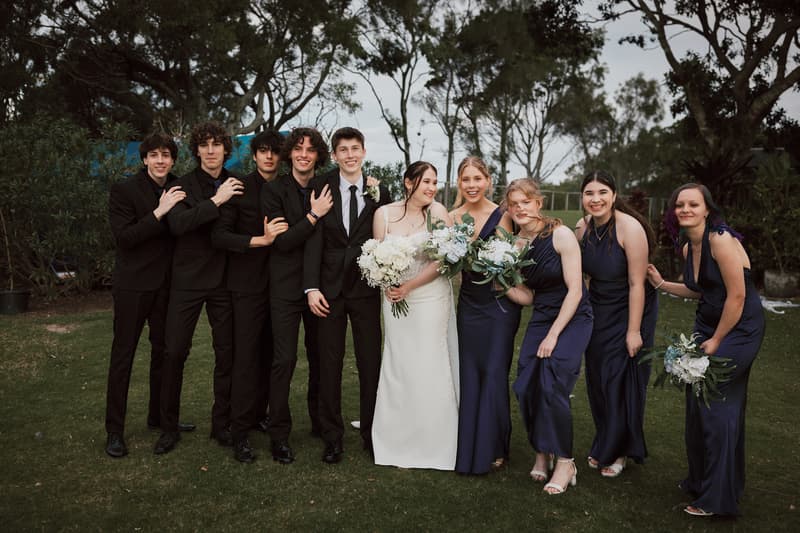 Terion the bride and Tyler the groom pose with their bridesmaids and groomsmen outdoors at Sandstone Point Hotelallo during the couple portraits stage.